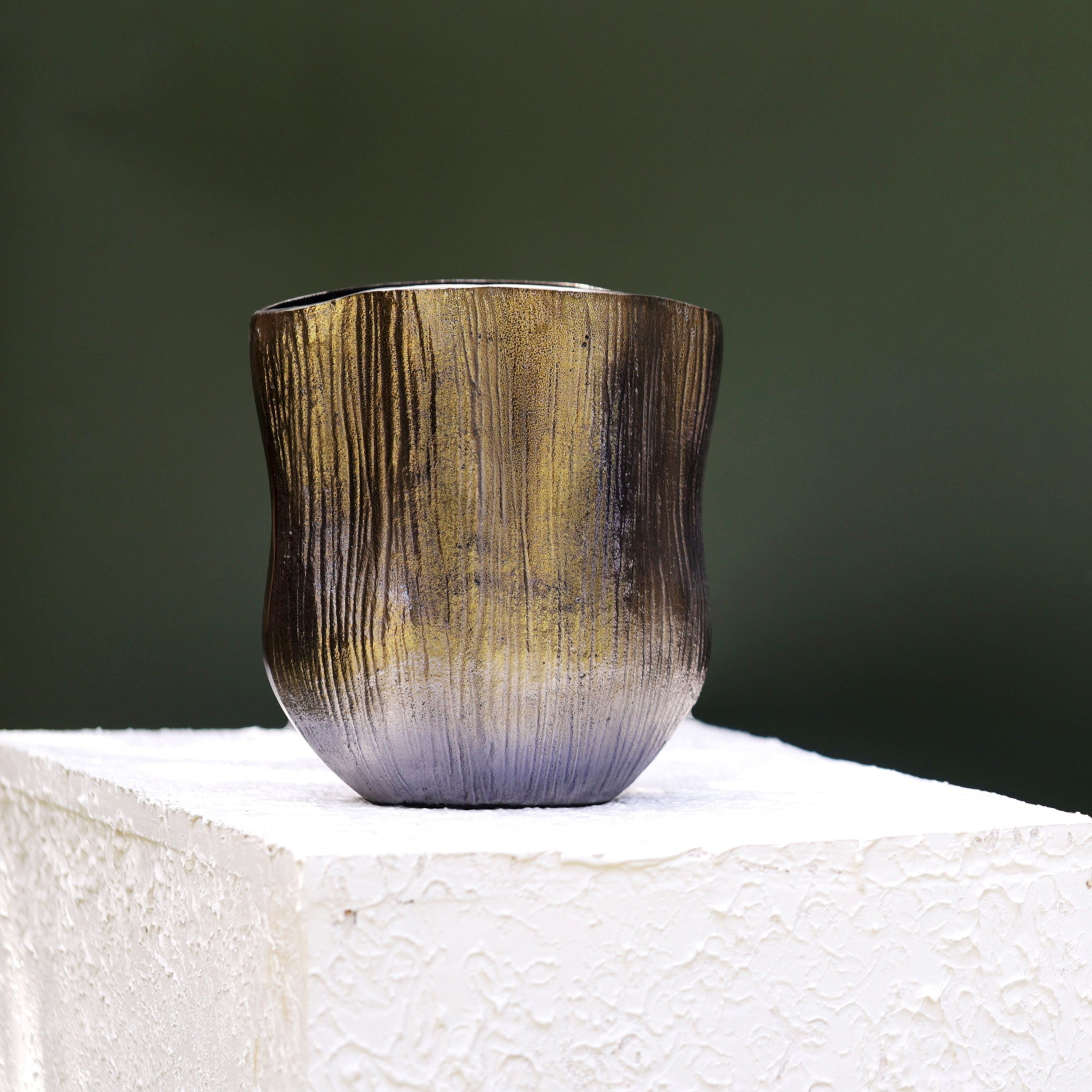 Handcrafted metallic vase with a tall, curved silhouette, featuring an ombré finish blending antique gold and smoky black tones. The vertical etched texture adds a rustic charm, making it a perfect centerpiece for modern or bohemian home décor styles.